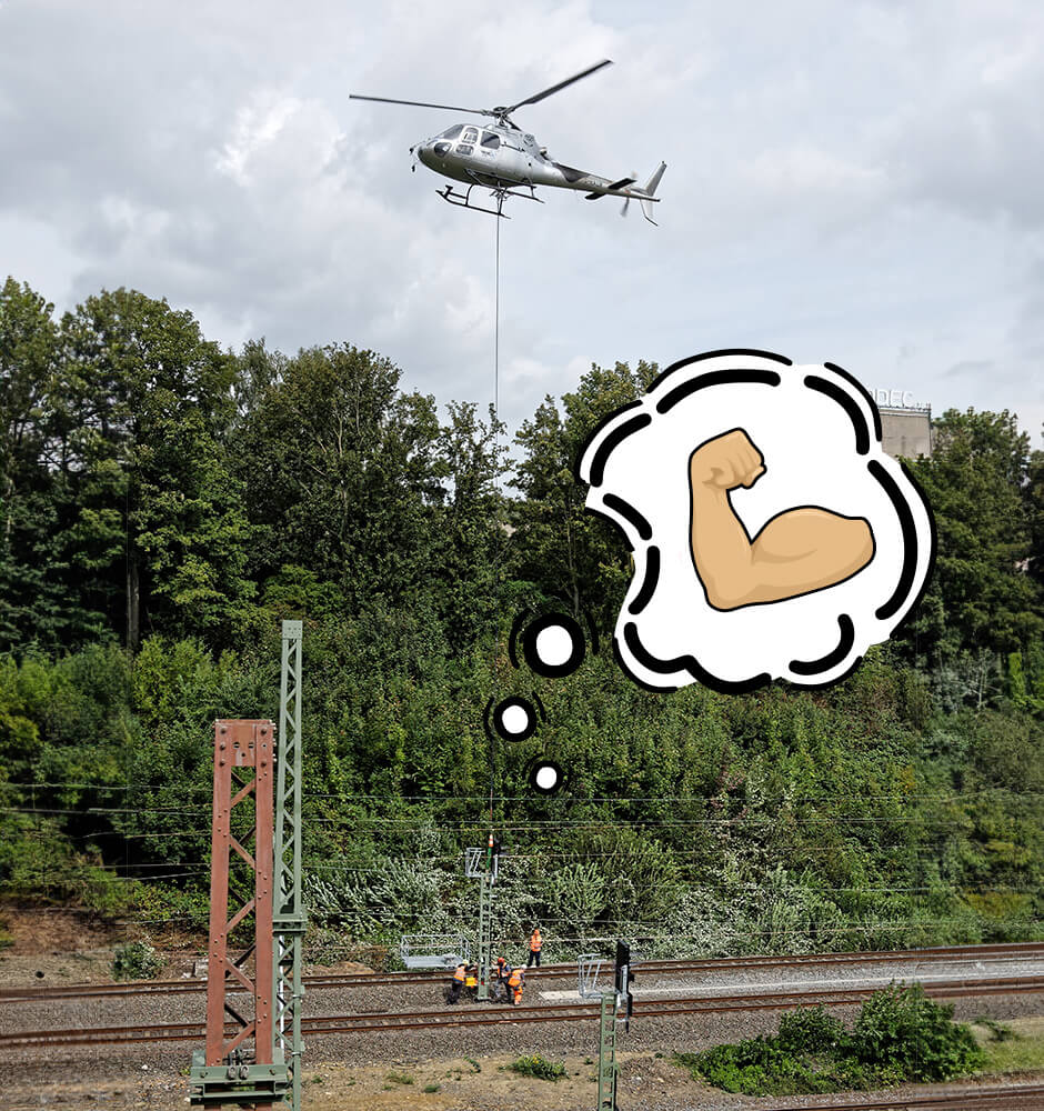 Ein Hubschrauber bringt Bauteile an einem Seil hängend an die Gleise