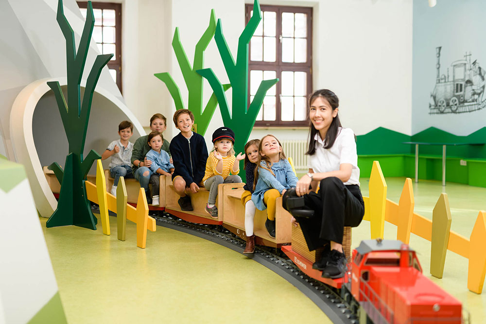 Kinder fahren auf einer Holzeisenbahn im DB-Museum